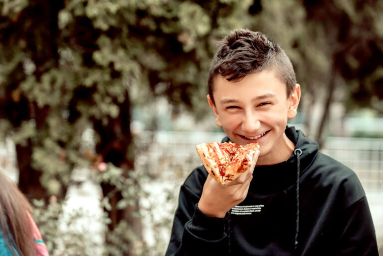 A boy eats pizza on a lunch break at school. Selective focus.