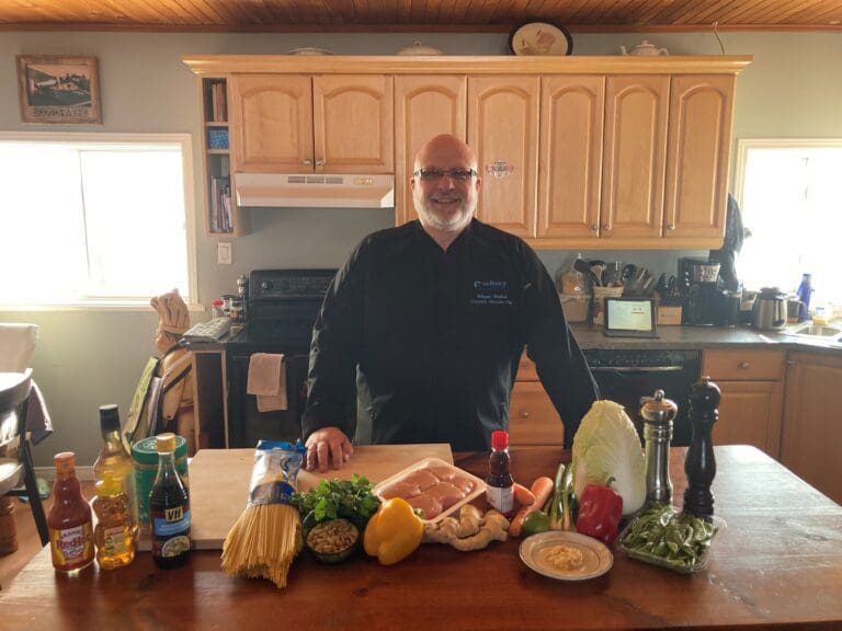 A picture of Chef Wayne standing in the kitchen with some ingredients in front of him